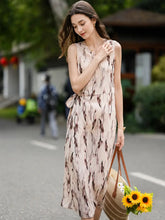 Model wearing a Sleeveless Floral Maxi Mulberry Silk Dress, walking outdoors with a straw bag and sunflowers.