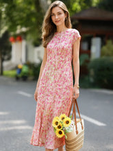 Elegant Floral Maxi Mulberry Silk Dress worn by a woman holding sunflowers in a straw bag in a sunny outdoor setting.