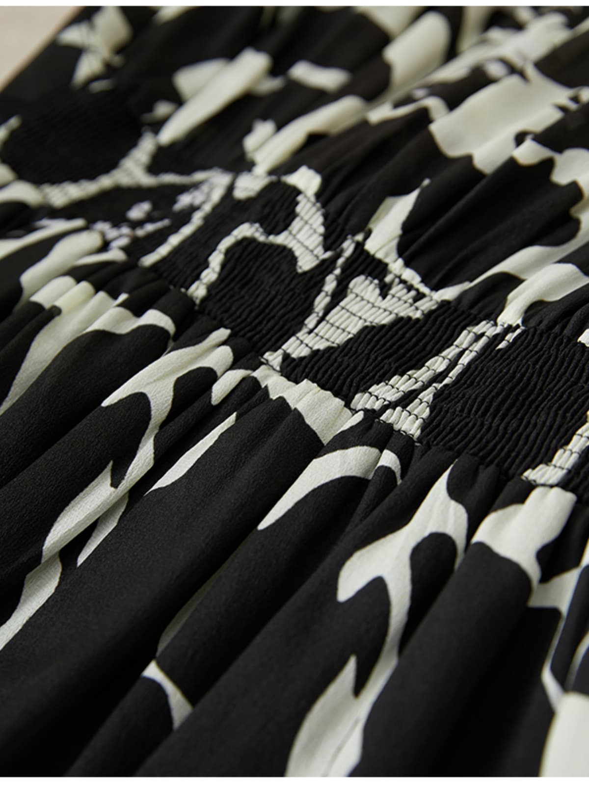 Floral Mulberry Silk Dress detail showcasing the elegant black and white floral pattern and smocked fabric texture.