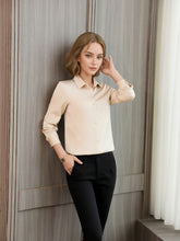 A model wearing a Women's Refined Minimalist Silk Blouse in beige, styled with black pants against a wooden backdrop.