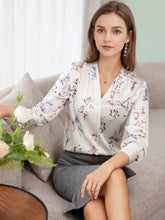 Woman wearing a Floral Mulberry Silk Blouse with a grey skirt, showcasing a stylish look in a serene indoor setting.-SILKSER