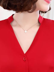 A close-up of a woman's neck and collar featuring a Trendy Silk Women's Blouse in red, complemented by a delicate necklace.