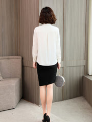 Back view of a woman in a white Versatile Mulberry Silk Blouse paired with a black skirt, highlighting elegant style.