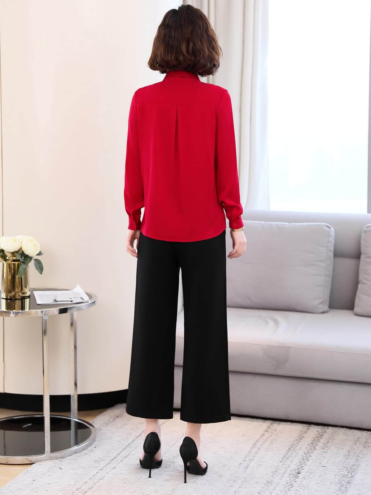 Back view of a woman wearing a Versatile Mulberry Silk Blouse in red with black culottes, showcasing style and elegance.