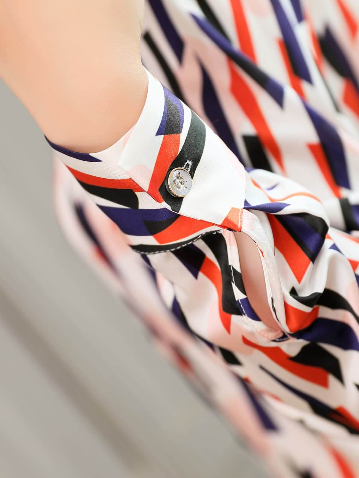 Close-up of the sleeve detail of the Women's Geo - Print Casual Silk Blouse featuring vibrant color patterns.