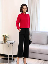 Woman wearing a red collared blouse with black trousers, showcasing a stylish outfit in a modern living space.