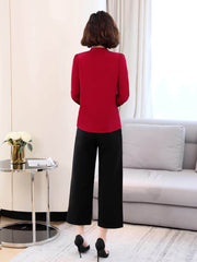 Back view of a woman wearing a red Ribbon Tie Mulberry Silk Blouse paired with black pants, standing in a modern living room.