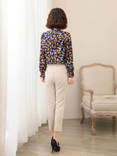 Woman wearing a Vintage Floral Mulberry Silk Blouse, viewed from the back, paired with beige trousers in a stylish setting
