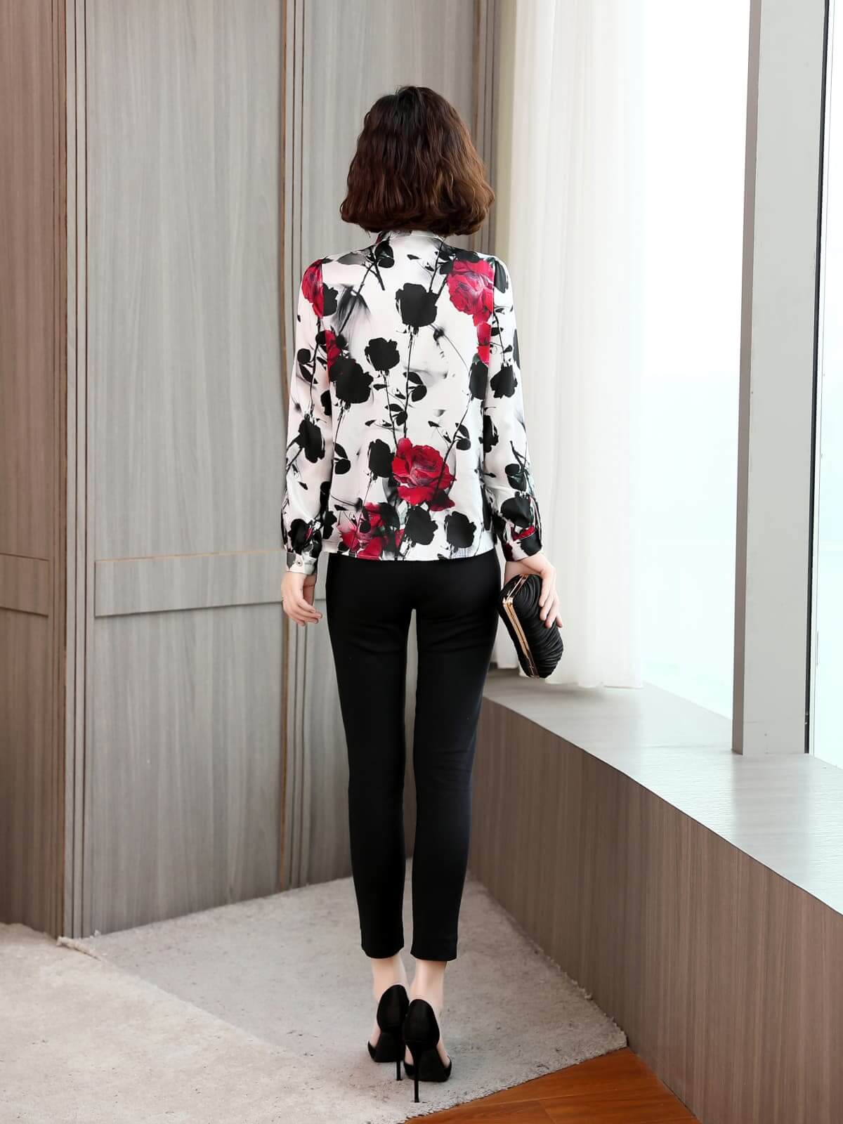 Woman wearing a Bow Tie Printed Mulberry Silk Blouse with floral design, paired with black pants.