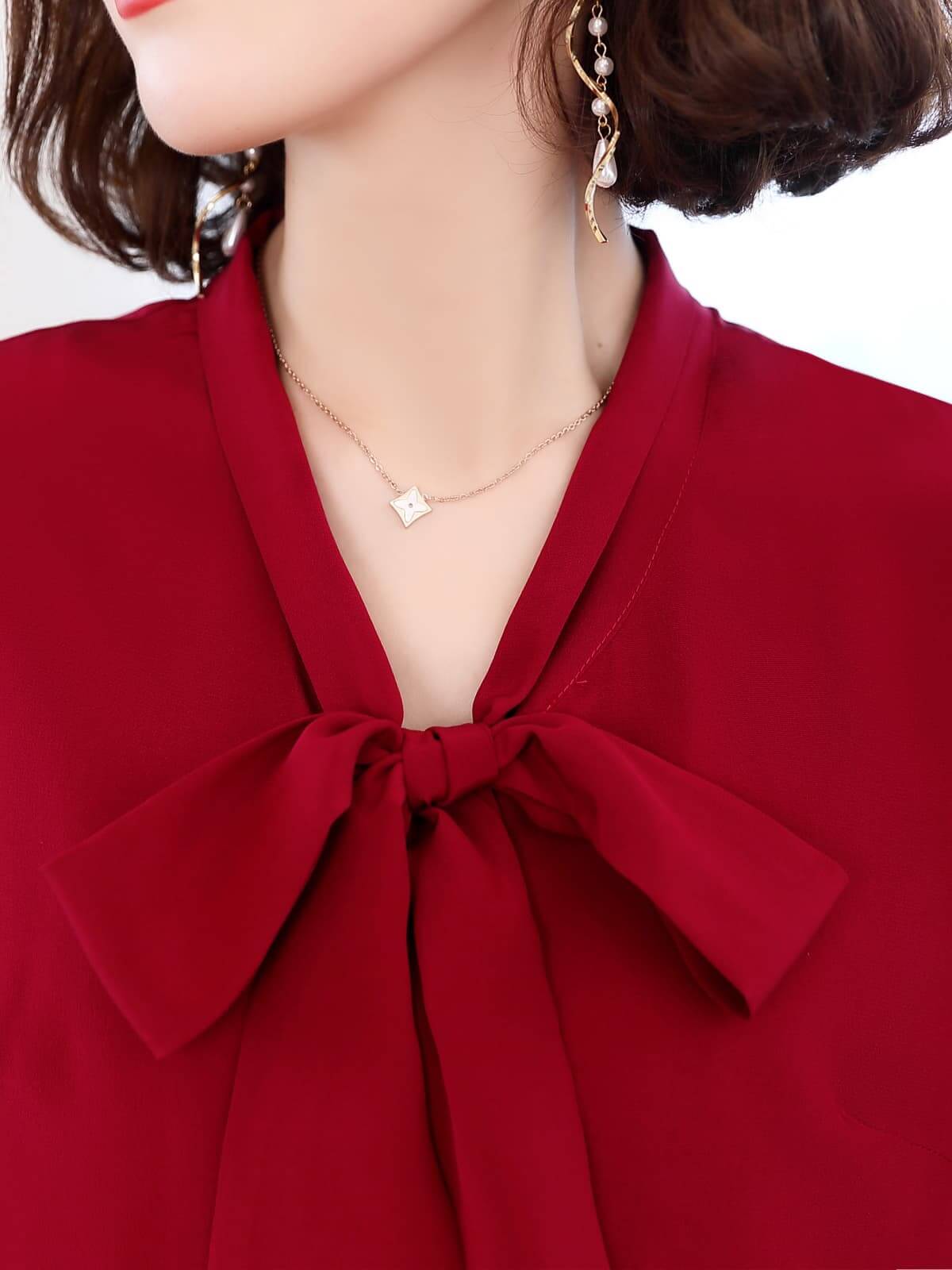 Close-up of a woman wearing a Ribbon Tie Mulberry Silk Blouse, showcasing the elegant bow and deep burgundy color.