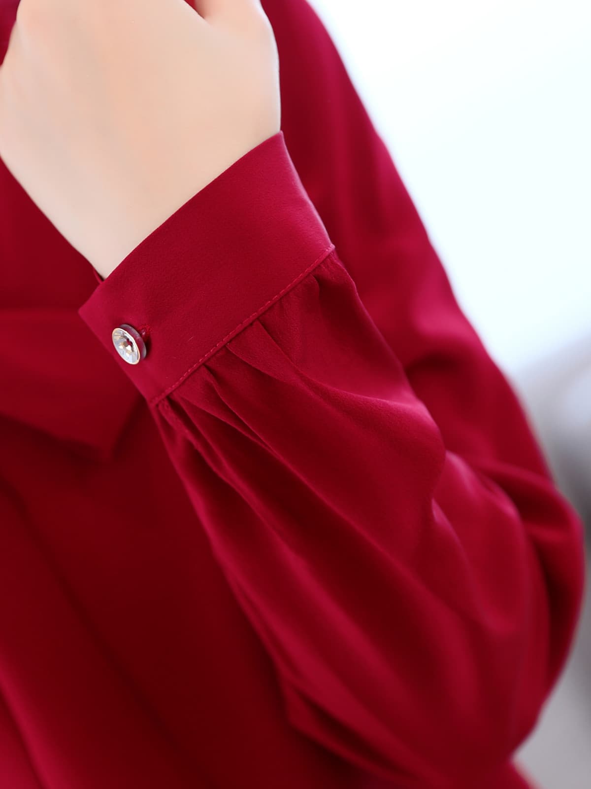 Close-up of the sleeve and cuff of the Ribbon Tie Mulberry Silk Blouse for Women in deep red color.