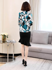 Woman wearing a Bow Tie Printed Mulberry Silk Blouse with a black skirt and heels, styled in a modern interior.