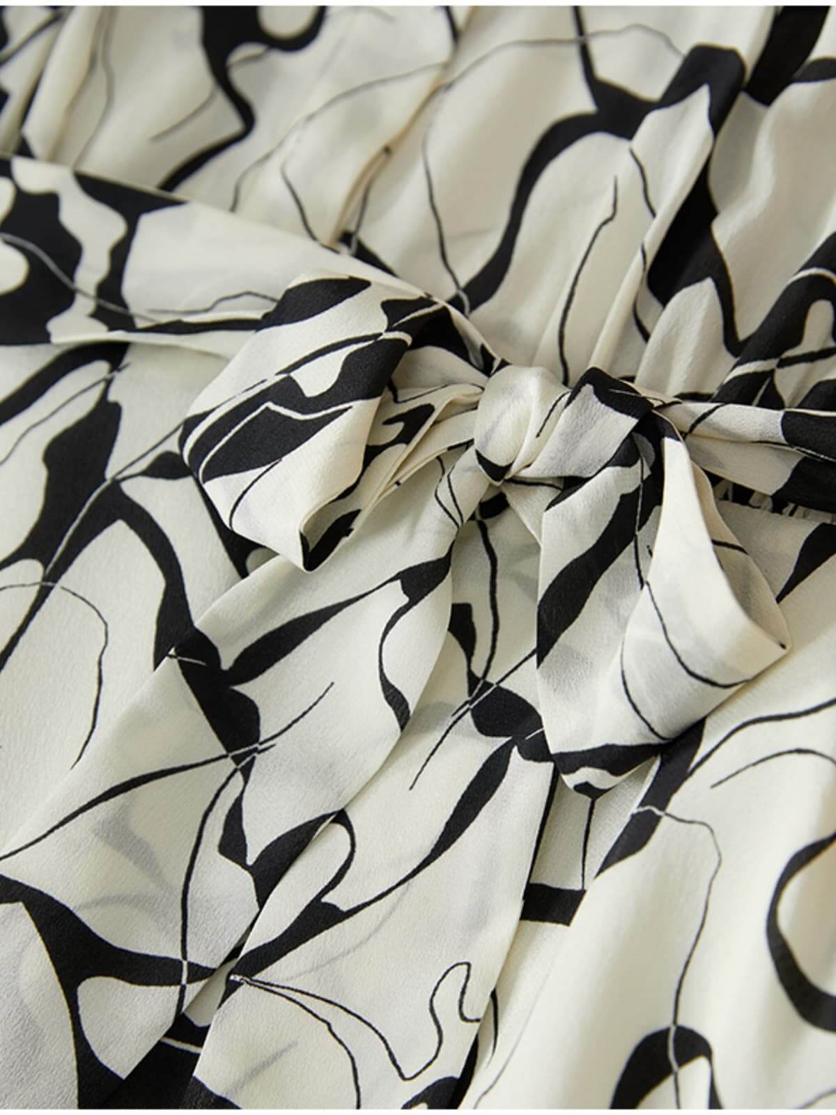 Close-up of the bow detail on a Breathable Mulberry Silk Shirt Dress featuring a floral pattern.