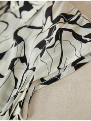 Close-up of the sleeve detail of a Breathable Mulberry Silk Shirt Dress featuring a modern abstract design.