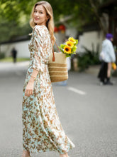 Woman wearing a Vintage Print Mulberry Silk Dress, holding a bag of sunflowers in a sunny outdoor setting.