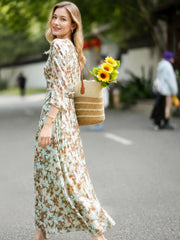 Woman wearing a Vintage Print Mulberry Silk Dress, holding a bag of sunflowers in a sunny outdoor setting.