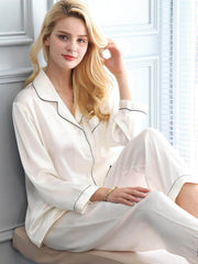 Model wearing Long - Sleeved Pure Silk Pajama Set for Women sitting on the sofa