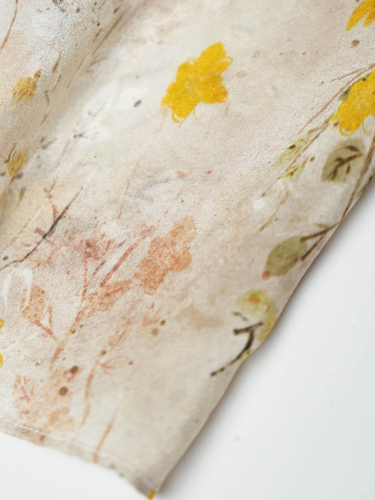Close-up of fabric showcasing floral design in soft cream and yellow hues for the French Floral Mulberry Silk Maxi Dress.